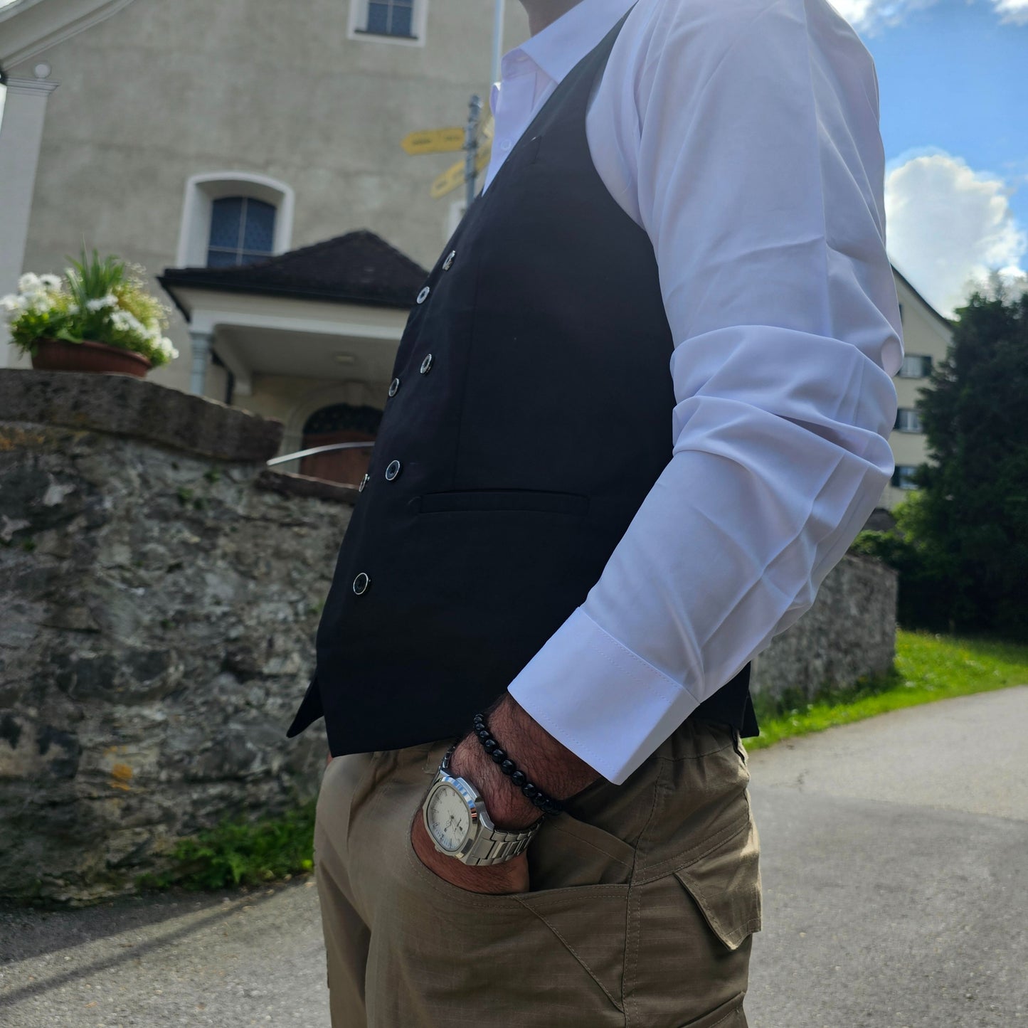 Side angle of sleeveless black polyester vest showing clean stitching and belt detail.